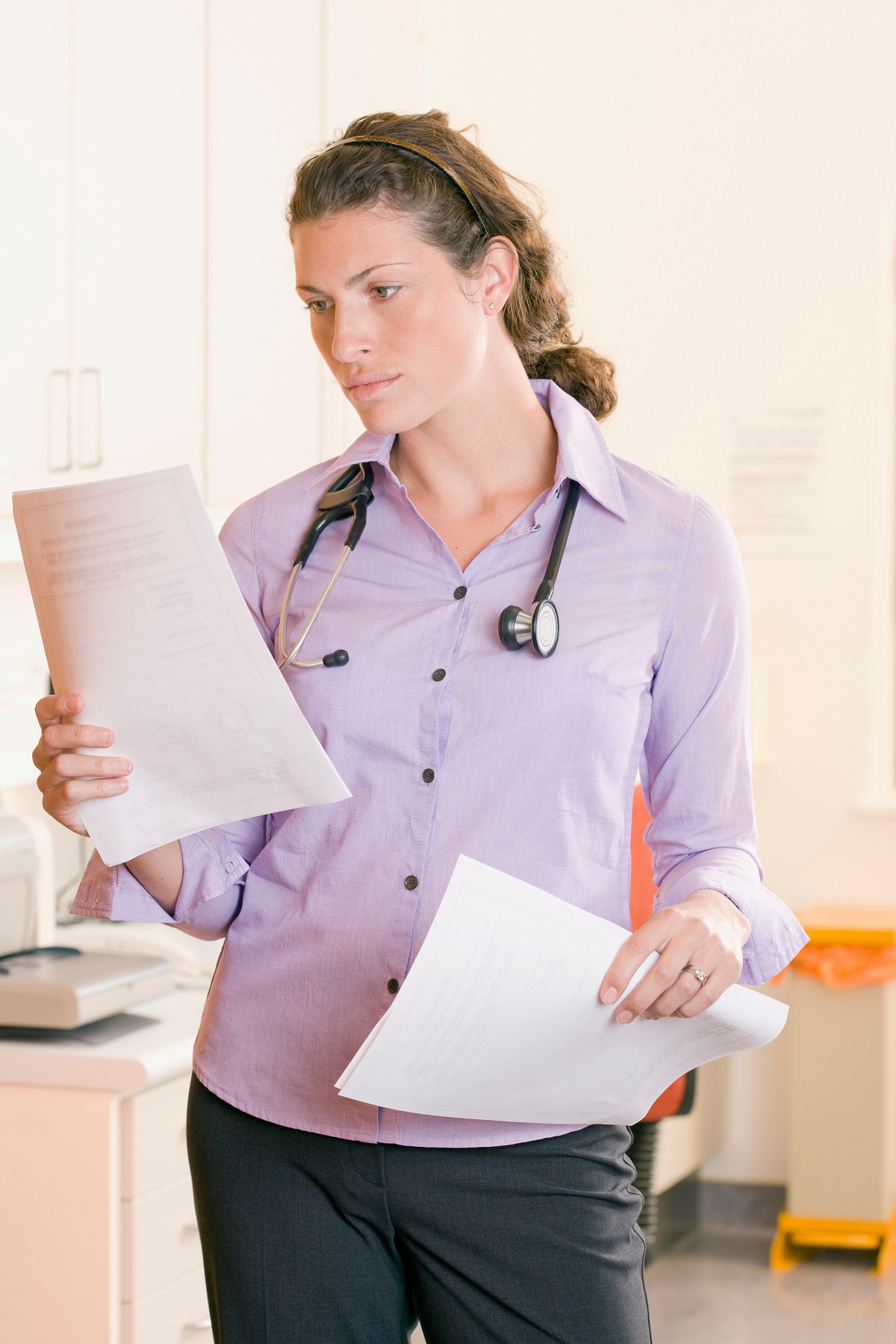 A woman with a stethoscope looking at documents