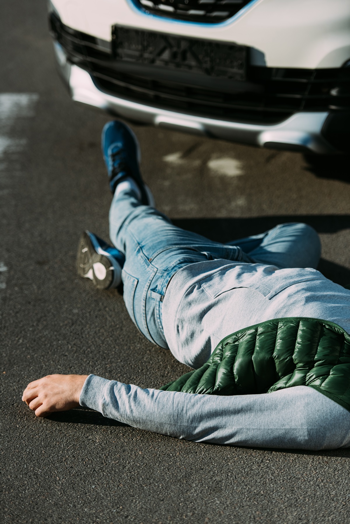 A car accident victim lying on the ground in front of a car