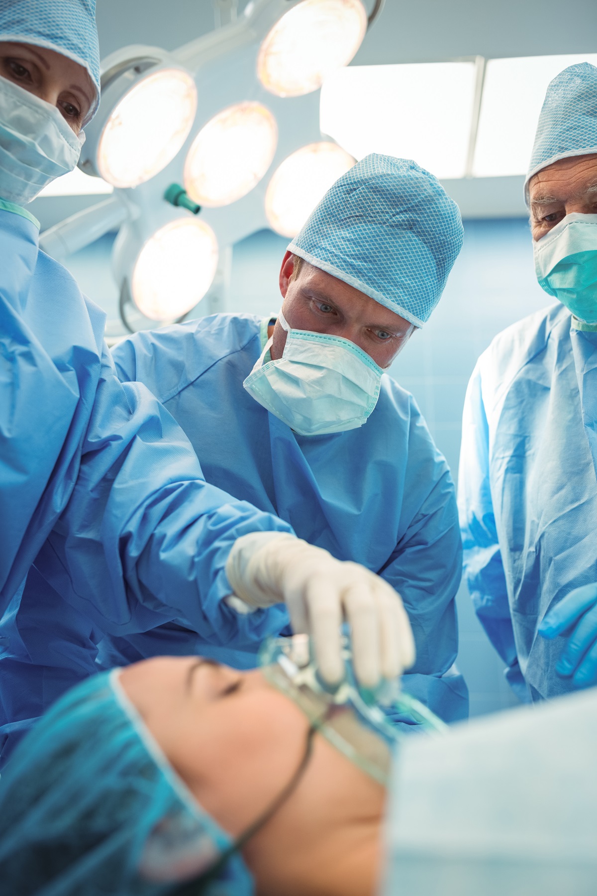 Healthcare providers standing around an unconscious patient with an oxygen mask