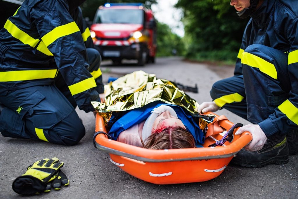 An injured person on a stretcher being attended to by two emergency responders