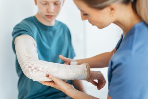 A healthcare provider checking a cast on the arm of an injured patient