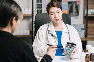 A healthcare provider using a calculator while speaking to a patient