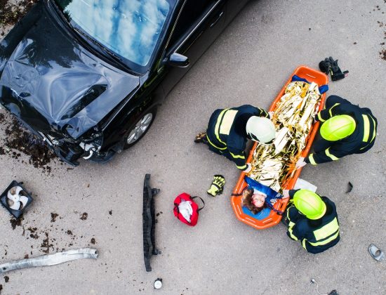 Emergency responders lifting an injured woman on a stretcher at the scene of a car accident