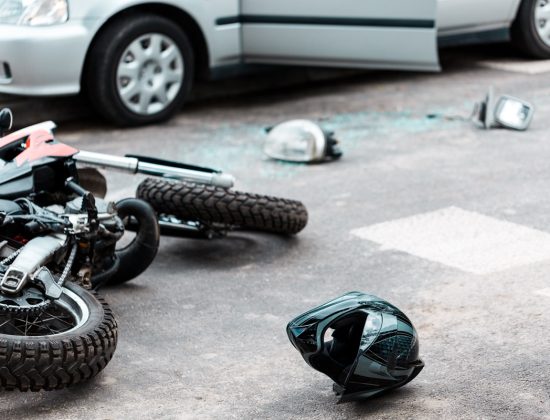An overturned motorcycle and helmet on the road after a car accident